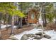 Charming log cabin surrounded by trees with wood pile and snow on the ground at 44 Linn Ln, Golden, CO 80403
