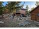 Back of home with a garage below and separate shop, surrounded by native vegetation and rock landscaping at 44 Linn Ln, Golden, CO 80403
