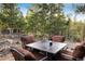 Outdoor seating with table, wine, and cushioned chairs surrounded by a beautiful wooded landscape at 44 Linn Ln, Golden, CO 80403