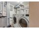 Functional laundry room with modern washer and dryer, storage shelves, and utility connections at 4468 S Zenobia St, Denver, CO 80236