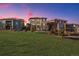 Backyard view of homes with patios, balconies, and lush green lawn and colorful dusk sky at 10659 Montecito Dr, Lone Tree, CO 80124