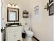 Charming half bathroom features a vanity with granite countertop, ornate mirror, decorative shelves, and a toilet at 10041 Dillon Cir, Commerce City, CO 80022