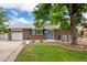 Inviting brick home featuring a well-kept lawn, charming blue door, and an attached one-car garage at 1011 Yeager Dr, Longmont, CO 80501