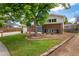 Charming two-story brick home with a well-manicured lawn, mature tree, and a bright blue front door at 1011 Yeager Dr, Longmont, CO 80501
