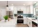 Bright kitchen with stainless steel appliances, white cabinets, quartz countertops, and a modern blue tile backsplash at 1011 Yeager Dr, Longmont, CO 80501