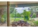 View of the manicured backyard with a stone waterfall and garden, seen through a sliding glass door at 8300 W 67Th Ave, Arvada, CO 80004