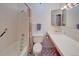 Bathroom with a combination tub and shower, featuring white tile and a decorative floor pattern at 8300 W 67Th Ave, Arvada, CO 80004