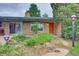 View of home exterior with established landscaping, exterior lighting, and beautiful front door at 8300 W 67Th Ave, Arvada, CO 80004