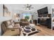 Comfortable living room featuring sofas, area rug, ceiling fan, fireplace with TV, and large window with natural light at 2295 Sandhurst Dr, Castle Rock, CO 80104