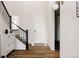 Bright entryway featuring wood floors, staircase with decorative iron railings, and modern light fixture at 5840 Longs Peak St, Brighton, CO 80601
