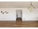 Spacious living room with modern light fixture, neutral paint, and wood floors flowing to the front entrance at 5840 Longs Peak St, Brighton, CO 80601