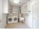 Clean laundry room with washer, dryer, utility sink, and ample shelving at 1059 Racine St, Aurora, CO 80011