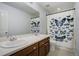 Bathroom showcasing a double sink vanity, large mirror, and butterfly-themed shower curtain at 16747 E 97Th Pl, Commerce City, CO 80022