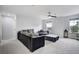 A modern living room with black leather furniture, a ceiling fan, and windows overlooking the surrounding landscape at 16747 E 97Th Pl, Commerce City, CO 80022