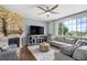 Bright living room with a stone fireplace, a ceiling fan, and plush seating arrangements at 16747 E 97Th Pl, Commerce City, CO 80022