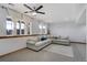 Bright living room featuring an oversized sectional sofa, large windows, and a ceiling fan at 16747 E 97Th Pl, Commerce City, CO 80022
