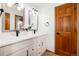Bathroom features double vanity with white marble countertops, modern fixtures, and warm wood door at 9983 Cottoncreek Dr, Highlands Ranch, CO 80130