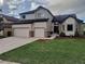 Two-story home featuring an attached three-car garage, a manicured lawn, and charming brick accents at 9983 Cottoncreek Dr, Highlands Ranch, CO 80130
