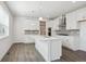 Kitchen with white cabinets, wood floors, and an island with a sink and overhead lights at 1876 Chaffee Crest Dr, Berthoud, CO 80513