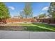 Large backyard with lawn, firepit area, rock garden, and a wood fence, providing a private outdoor space at 418 Hayloft Way, Brighton, CO 80601