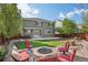 Spacious backyard with a fire pit, chairs, lush grass, and the exterior of the home at 418 Hayloft Way, Brighton, CO 80601