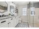 Elegant bathroom with dual sinks, patterned tile floor, and a glass shower enclosure at 418 Hayloft Way, Brighton, CO 80601