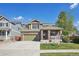 Charming two-story home featuring a brick facade, covered front porch, and well-maintained lawn under a bright blue sky at 418 Hayloft Way, Brighton, CO 80601
