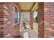 Inviting front porch featuring a porch swing, brick columns, and decorative hanging planters with string lights at 418 Hayloft Way, Brighton, CO 80601