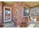 Inviting front porch with a porch swing, decorative plants, string lights and brick columns, offering a relaxing outdoor space at 418 Hayloft Way, Brighton, CO 80601