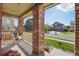Cozy porch featuring a porch swing, decorative planters, and charming brick columns, creating a welcoming space at 418 Hayloft Way, Brighton, CO 80601