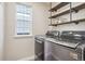 Modern laundry room equipped with stainless steel washer and dryer, and decorative wood shelving at 418 Hayloft Way, Brighton, CO 80601