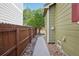 View of the exterior side yard with a stone-lined walkway, a wooden fence and a grass area at 418 Hayloft Way, Brighton, CO 80601