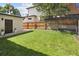 Large, fenced backyard with lush green grass and easy access to a detached garage at 505 Detroit St, Denver, CO 80206
