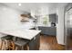 Modern kitchen with gray cabinets, marble countertops, stainless steel appliances, and wooden floating shelves at 505 Detroit St, Denver, CO 80206