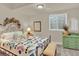 This bright bedroom has a patterned quilt, metal bed frame, and green painted dresser, all accented by a sunny window at 1982 Peralta Loop, Castle Rock, CO 80104