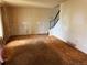 An empty living room featuring carpeted floors, a staircase with railing, and walls that are ready to be revitalized at 8779 Santa Fe Dr, Thornton, CO 80260