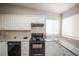 Modern kitchen with white cabinets, granite countertops, black appliances, and natural light from the window at 12555 Birch Ave, Thornton, CO 80241