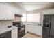 Modern kitchen with white cabinetry, granite countertops, black appliances and wood-style flooring at 12555 Birch Ave, Thornton, CO 80241