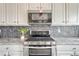 This kitchen features stainless steel appliances, a modern backsplash, and gray countertops at 1192 S Fultondale Cir, Aurora, CO 80018