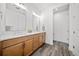 Bathroom with double vanity, wood cabinets, white countertop, gray wood-look tile floors, and decorative accents at 331 Josef Cir, Fort Lupton, CO 80621