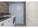 Functional laundry room equipped with modern appliances, wood paneling, and shelves for efficient storage at 649 Mockingbird St, Brighton, CO 80601