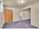Basement space features neutral walls, blue carpet, wood doors, and a long hallway at 5510 Troy St, Denver, CO 80239
