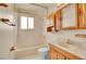 Bright bathroom features a shower-tub combo, a window, and a wood vanity with ample storage at 5510 Troy St, Denver, CO 80239
