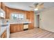 Functional kitchen features wood cabinetry, white appliances, and a window offering natural light and backyard views at 5510 Troy St, Denver, CO 80239