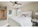 Sunlit primary bedroom featuring a fluffy white bedspread, side table, and ample space at 2042 Shadow Creek Dr, Castle Rock, CO 80104