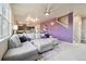 Stylish living room featuring a large sectional sofa, purple accent wall, and open floor plan at 2042 Shadow Creek Dr, Castle Rock, CO 80104