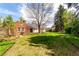 Lush backyard of a brick home with a sprawling lawn and mature trees, offering privacy and space at 3756 S Forest Way, Denver, CO 80237