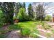 Secluded backyard with mature trees, landscaped garden beds, and a stone pathway, perfect for relaxation at 3756 S Forest Way, Denver, CO 80237
