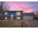 Updated blue home with brick skirt and attached garage at dusk at 15934 E Columbia Pl, Aurora, CO 80013