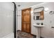 Modern bathroom features a pedestal sink, wood door, black framed mirror, and a glass-enclosed shower at 5694 S Pagosa Ct, Centennial, CO 80015